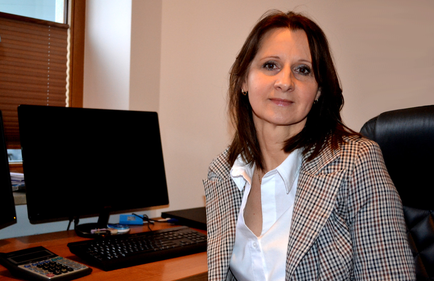 A woman in glasses (office owner) sitting at the desk.